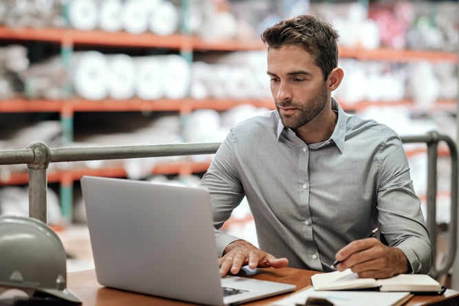 Warehouse manager using a laptop.