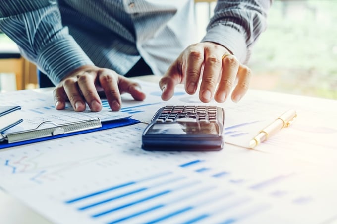 Male hands using a calculator around spreadsheets