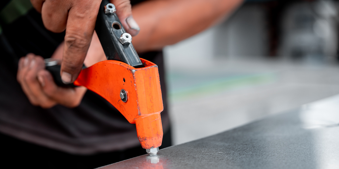 Professional using a threaded insert riveter to install a rivet on a metal surface